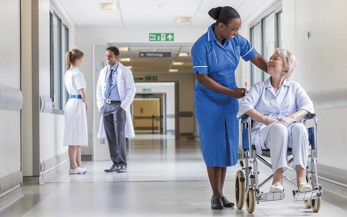 Nurse in corridor with patient in wheelchair